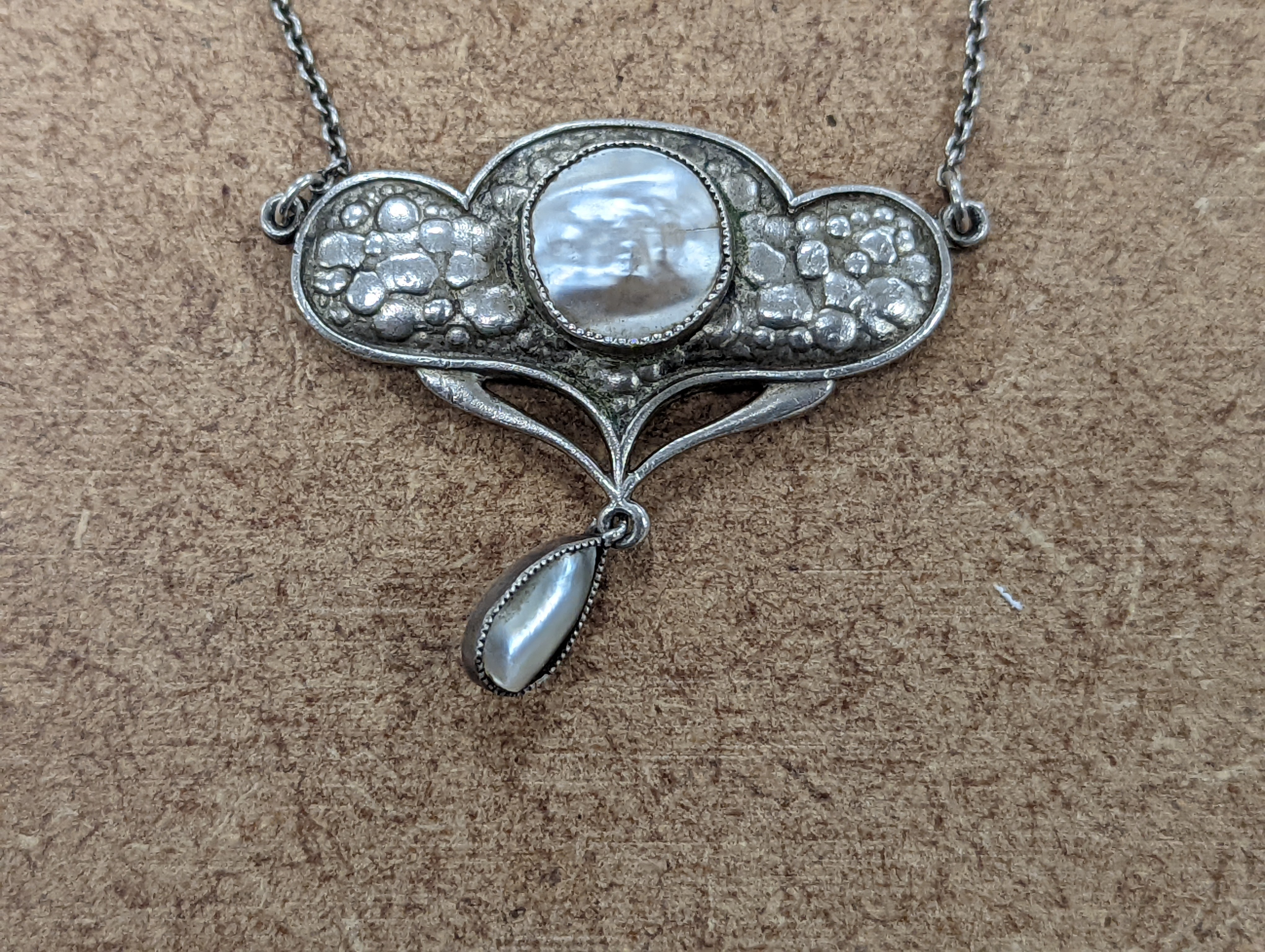 An Art Nouveau style sterling and mother of pearl set pendant necklace, stamped Queensway, 62cm and a white metal bangle.